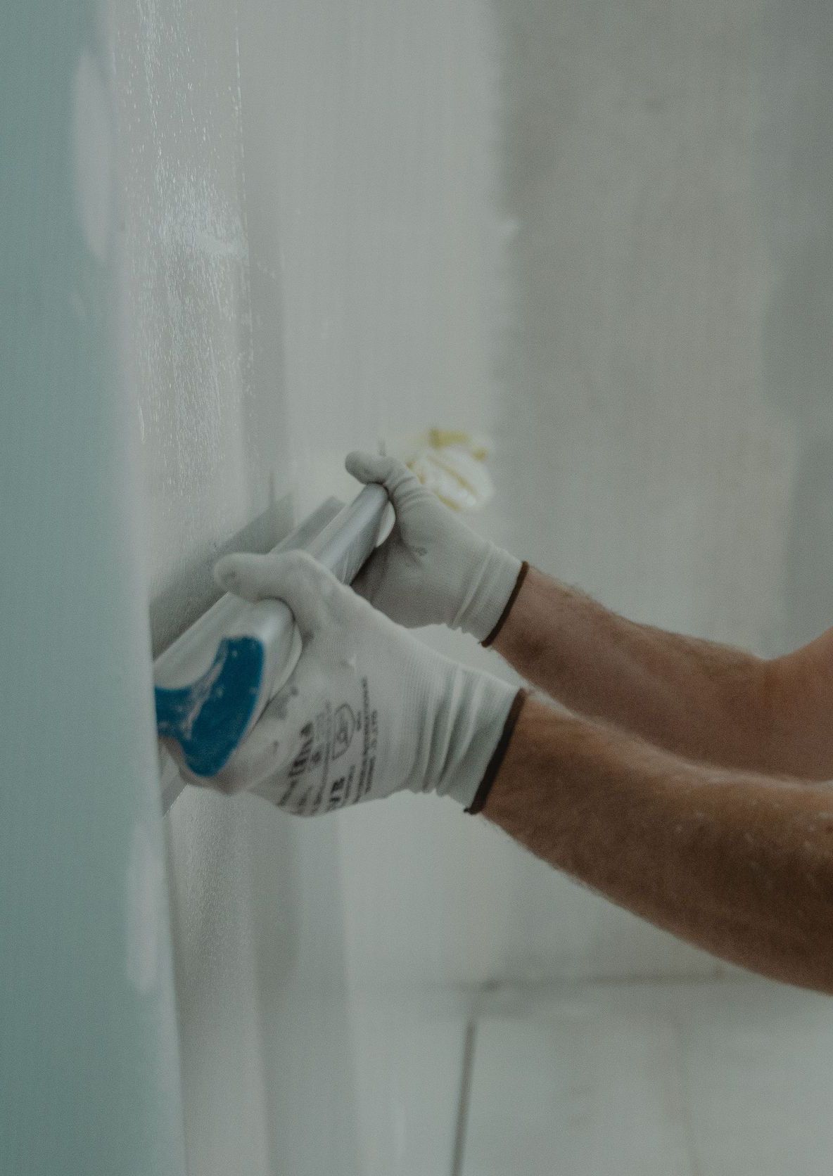 A focused worker applying drywall compound during a home renovation project indoors.